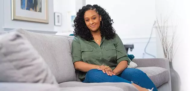 Tia Mowry sitting on a couch.