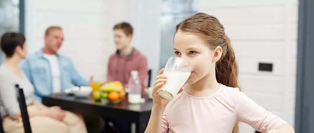 photo of Healthy girl drinking milk from glass in the kitchen