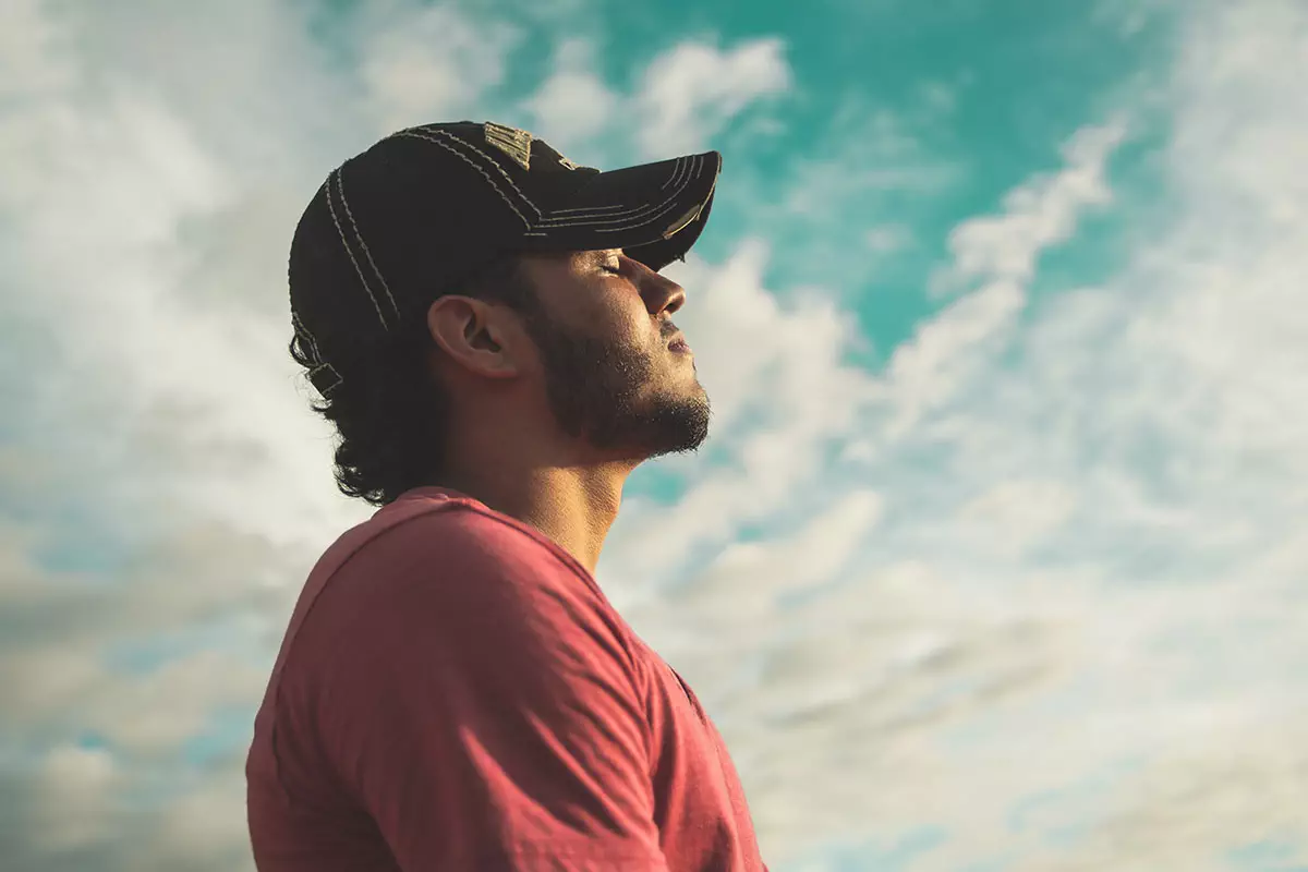 photo of man wearing a black baseball cap looking into the distance