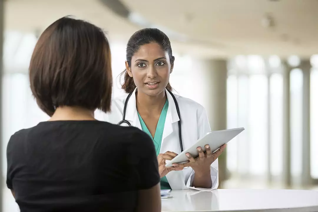 Photo looking over the shoulder of a patient having a conversation with a  doctor