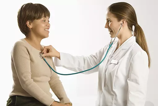 Photo of woman being examined by a doctor with a stethoscope