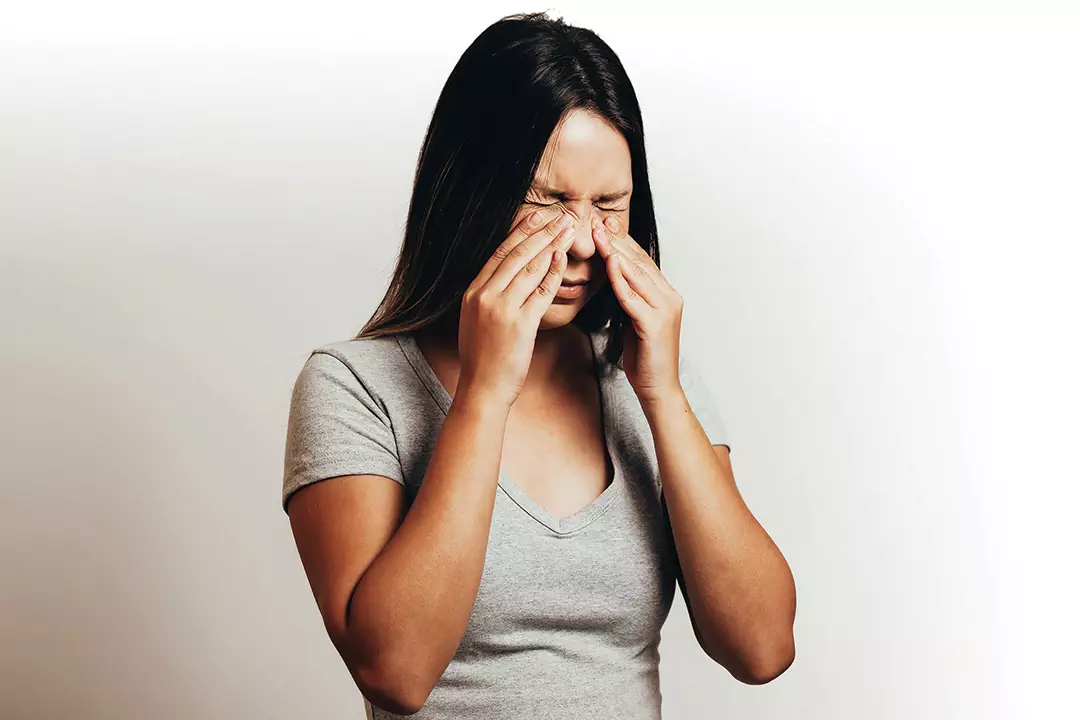 photo of woman with sinus pain touching her sinus area on her face