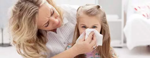 Mom wiping the nose of her young daughter with allergies, before sending her off to school.