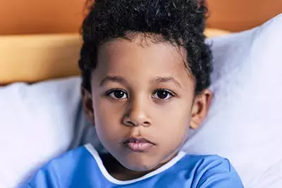 Photo of hispanic boy in hospital laying on pillow