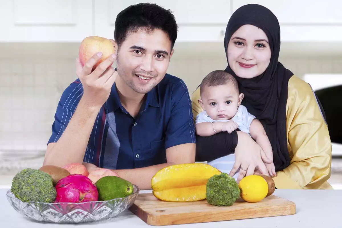 Portrait of healthy asian family smiling at the camera while sitting in the kitchen with fresh fruits