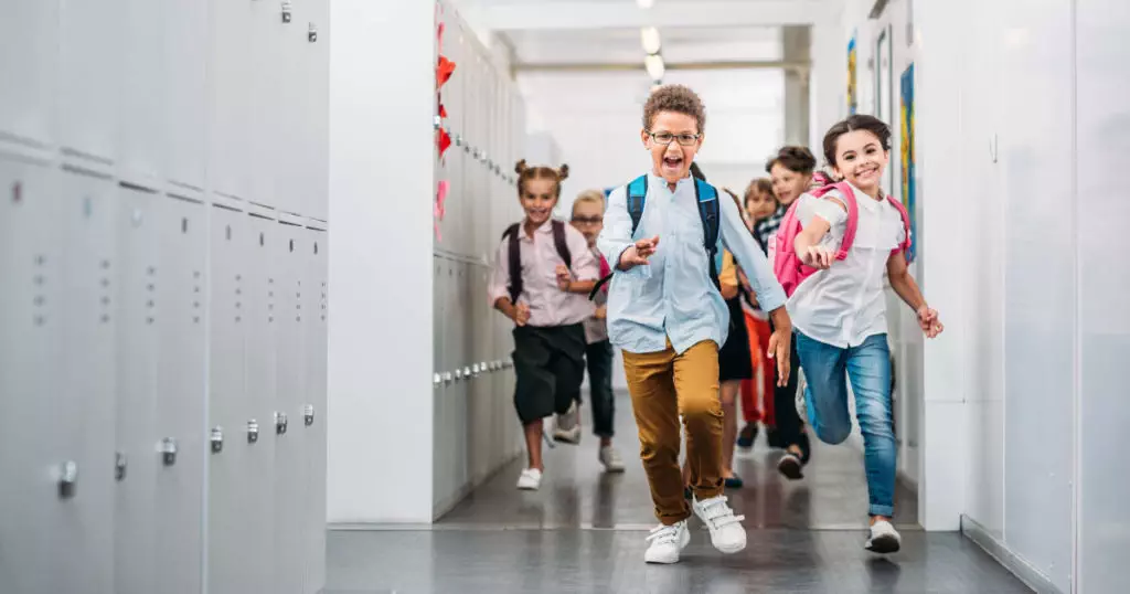 Photo of children running down the hallway of a school