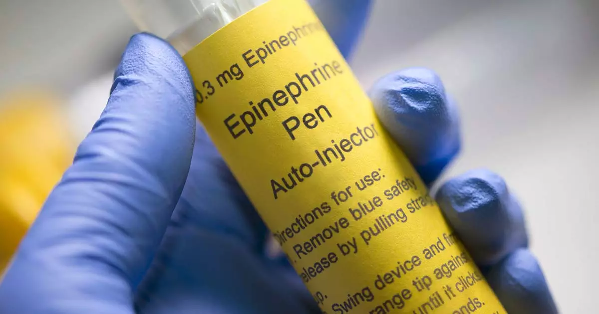 Close-up of hand wearing a blue surgical glove is holding an epinephrine pen auto injector