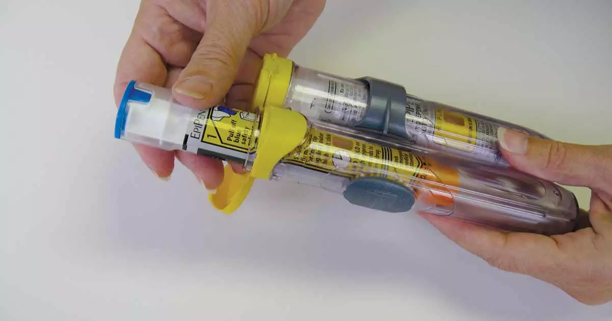 Woman's hands holding two autoinjectors of epinephrine