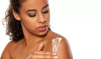 Photo of woman placing lotion on her shoulder