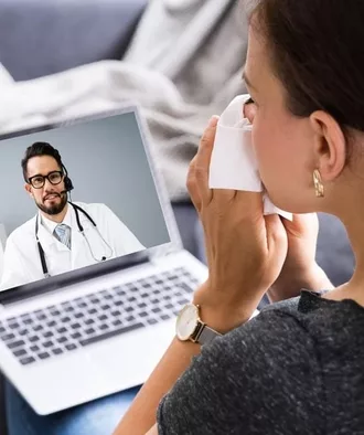 Woman holding a tissue to her nose during a telehealth online visit with her allergist