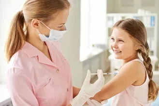 Photo of Adorable girl looking at nurse while she making her an injection in clinics