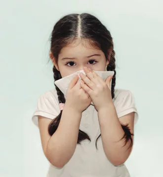 Young Latina girl holding tissue to her nose because of allergic rhinitis