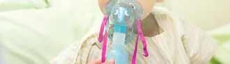 Sick young boy, 3 years old, inhale medication by inhalation mask to cure Respiratory Syncytial Virus (RSV) on hospital bed.