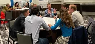 photo of attendees of the in-person ICAN conference around a table