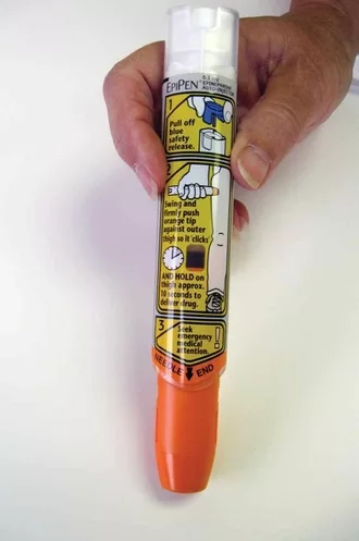 Person's hand holding an EpiPen so the label shows
