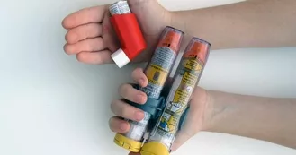 Kids hands holding two epipens in one and an inhaler in the other
