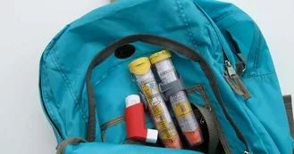Two EpiPens and an inhaler in the back of a backpack