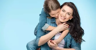 image of smiling white woman with a young girl wrapping her arms around her from behind