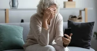 Older woman looking concerned and reading the Coughtracker app on her mobile phone.