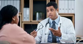 Doctor talking to patient in medical consultation, checkup and visit in clinic, hospital and healthcare center. Professional, gp and frontline worker explaining symptoms while asking woman questions.
