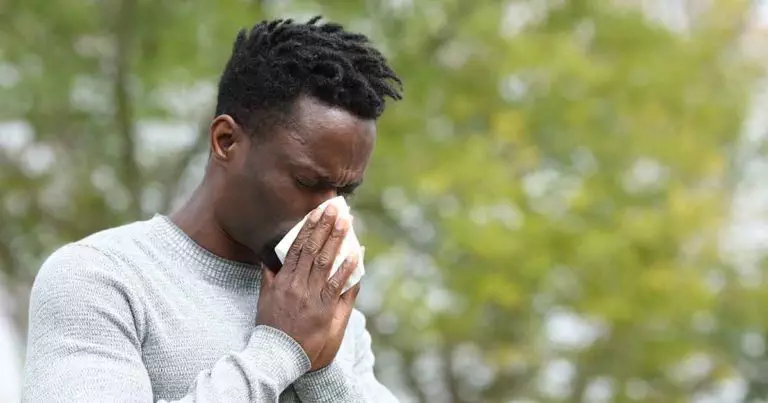 Photo of Allergic black man blowing on wipe in a park on spring season a sunny day